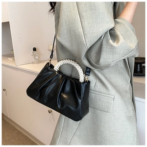 Detail of black pleated cloud bag featuring pearl handle and detachable crossbody strap