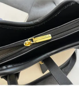 Close-up of smooth gold metal zipper and herringbone lining on contrast bucket bag
