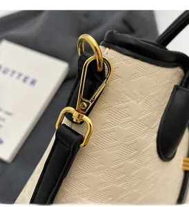 Detail of premium gold-tone lobster clasp and textured cream leather bucket bag strap