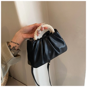 Detail of black pleated cloud bag featuring a pearl bead handle and slim leather strap