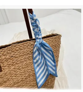 Detail of blue and white striped silk scarf tied on a brown woven straw bag handle