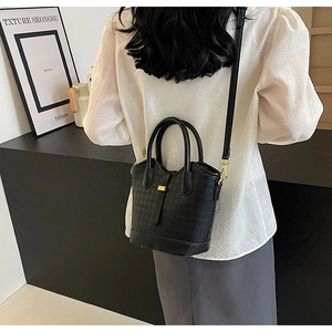 Asian model showing black houndstooth pattern bucket bag with golden hardware and strap