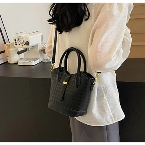 Detail view of the black houndstooth pattern and gold hardware on a chic bucket bag