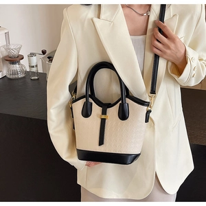 Detail of a chic cream and black contrast tote bag with elegant gold buckle and shoulder strap