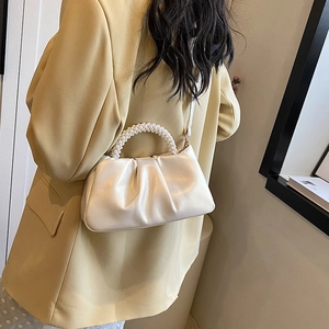 Elegant white pleated cloud bag featuring a pearl bead handle and slim shoulder strap