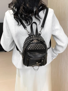 Mini black PU leather backpack with silver rivets and punk cross charm worn by model