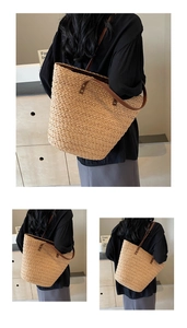 Detail of summer straw woven tote bag with brown leather straps shown on a model