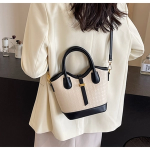 Side view of chic houndstooth bucket bag in beige and black worn by a female model