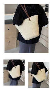 Detailed close-up of woven raffia texture and brown leather straps on a cream tote bag