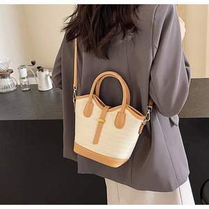Detail showing contrast color bucket bag with woven texture and gold metal buckle