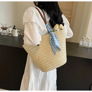 Detailed view of handmade woven straw tote bag with brown straps and silk scarf