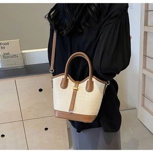 Close-up of contrast bucket bag with houndstooth texture and gold metal hardware