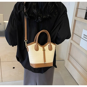 Detail of bicolored bucket bag showing woven texture and brown leather stitching trim