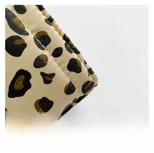 Macro detail of leopard print quilted fabric with fine golden stitching on large tote bag