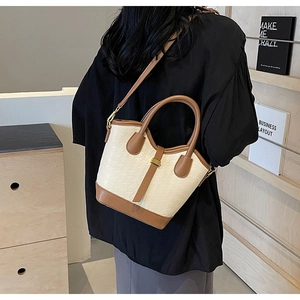 Close-up of contrast bucket bag with beige textured leather and brown strap detail
