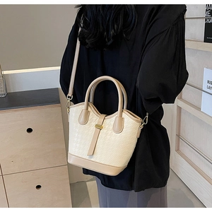 Detail of elegant two-tone beige bucket bag with houndstooth texture and gold buckle