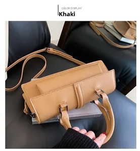 Détail du sac à bandoulière en cuir mat kaki avec ferrures métalliques gris foncé sur noir