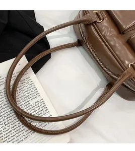 Close-up of shoulder strap connection and gold metal zipper on dark brown PU leather bag