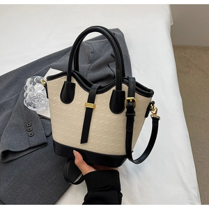 Detail of elegant cream and black contrast handbag with golden hardware and textured finish
