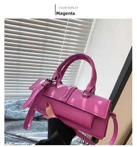 Détail du sac baguette rose rouge brillant avec bandoulière réglable et boucle en métal