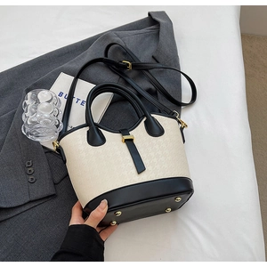 Detail view of contrast bucket bag showing houndstooth texture and golden hardware accents