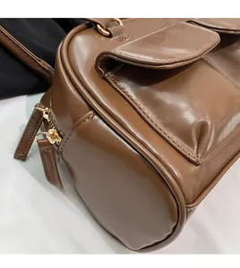 Close-up of the smooth dark brown PU leather surface and neat stitching on a shoulder bag