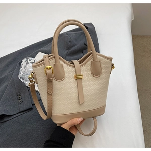 Detail of beige bucket bag showing embossed houndstooth texture and gold hardware
