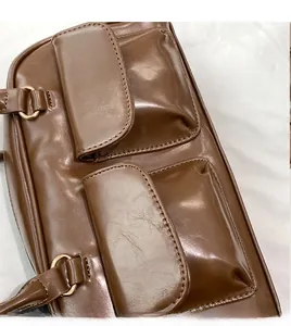 Detail of brown PU leather handbag with dual front pockets and gold metal buckles