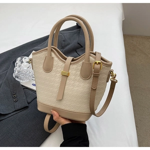 Detail of beige bucket bag with houndstooth embossing and elegant gold hardware buckle