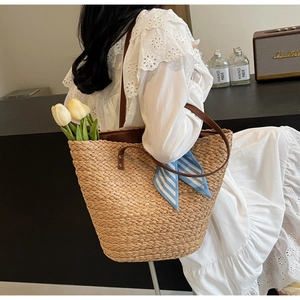 Detail of bohemian raffia woven tote bag with brown leather handles and summer silk scarf