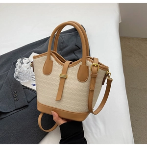 Detail of beige and brown contrast handbag with houndstooth texture and gold hardware