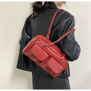Macro shot of red faux leather shoulder bag with golden zippers and front flap pockets