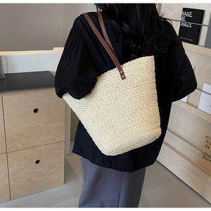 Detail of raffia woven tote bag showing sturdy weave texture and leather shoulder straps