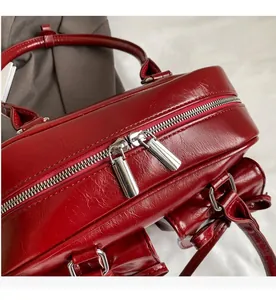 Detailed view of silver dual-zipper closure on a burgundy patent leather tote bag
