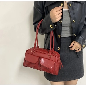 Detail of red faux leather tote bag with external flap pockets and gold hardware