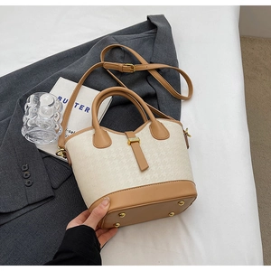 Detail of contrast color bucket bag with houndstooth pattern and gold metal hardware