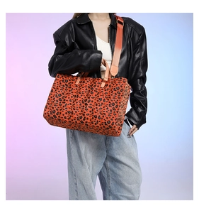 Macro detail of leopard print tote bag with leather handle and orange textile strap