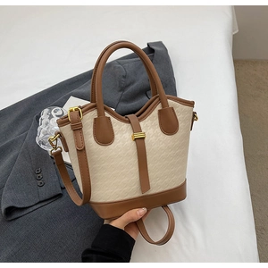 Detail of houndstooth canvas bucket bag with brown leather trim and golden metal buckles