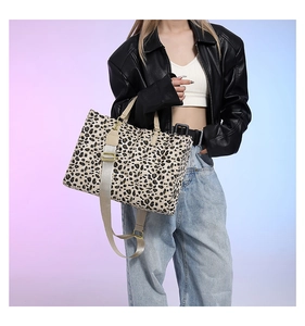Close-up of leopard print tote bag with cream handles and adjustable gold-buckle strap