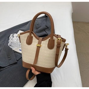 Detailed close-up of beige and brown bucket bag with houndstooth texture and gold hardware