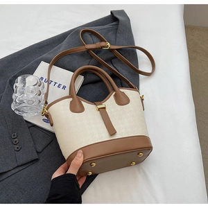 Detail of contrast bucket bag with houndstooth fabric, brown leather trim and gold studs