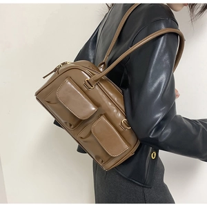 Detailed view of brown PU leather shoulder bag featuring dual front flap pockets