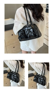 Detail of black glossy PU leather shoulder bag with decorative bows and silver zippers