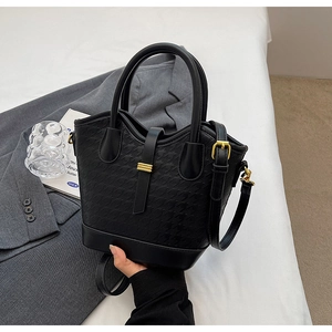 Detail showing classic black houndstooth pattern fabric and gold hardware buckle on a bucket bag