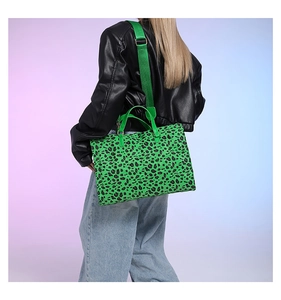 Detail view of neon green leopard print tote bag with wide strap on model's shoulder