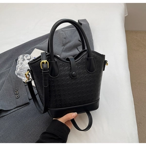 Detail of the black bucket bag showing houndstooth embossed texture and gold hardware