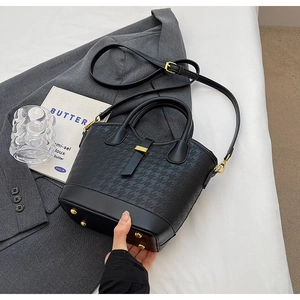 Detail view of stylish black bucket bag with houndstooth texture and gold protective studs