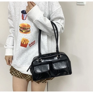 Detail of black glossy PU shoulder bag with dual front flap pockets and zip closure