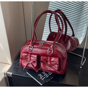 Macro detail of wine red PU leather boston bag with decorative bows and silver hardware