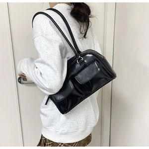 Detail shot of the black shiny PU leather hobo bag with gold zippers and pockets